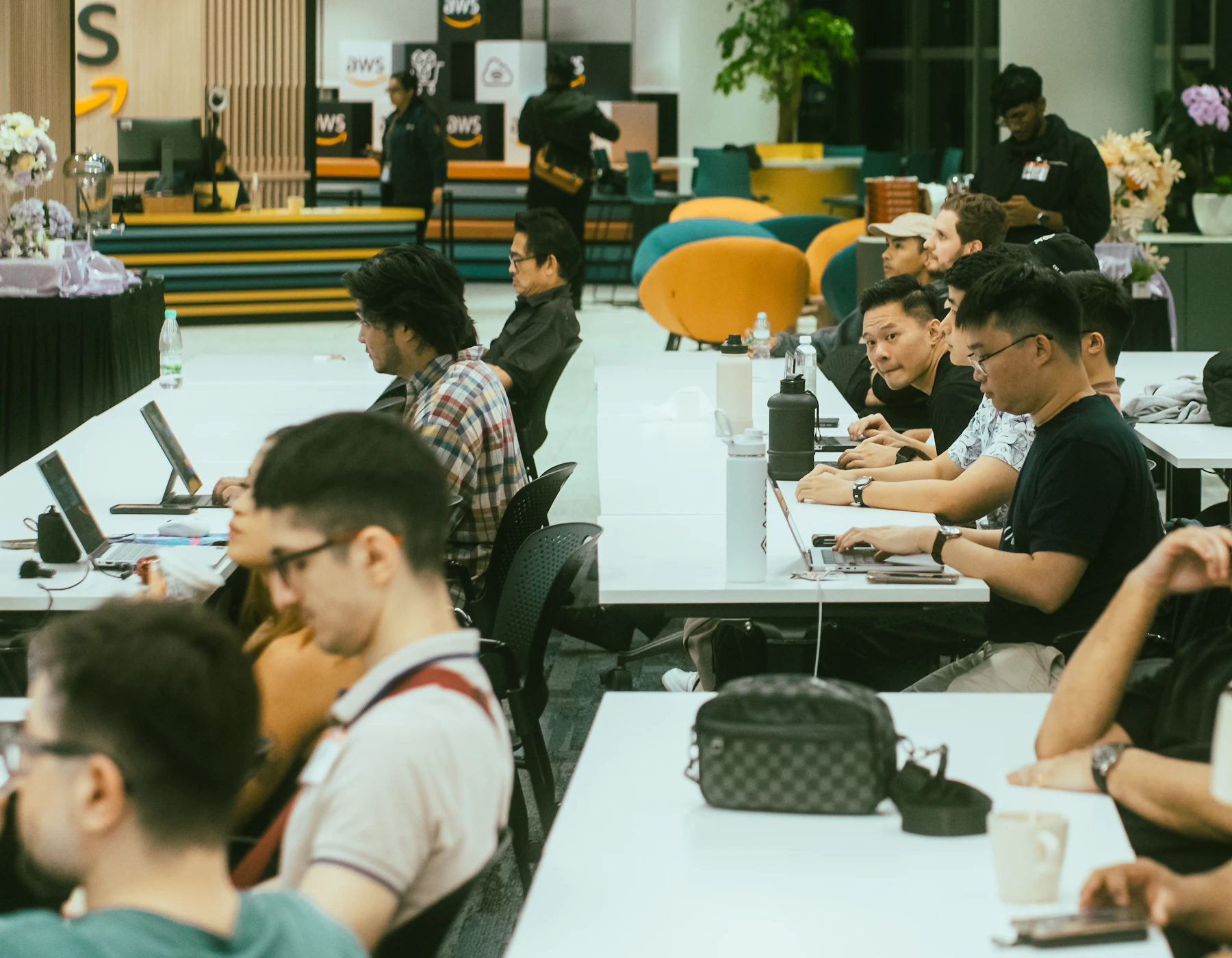 Masalarda laptoplarıyla çalışan kalabalık bir hackathon salonu